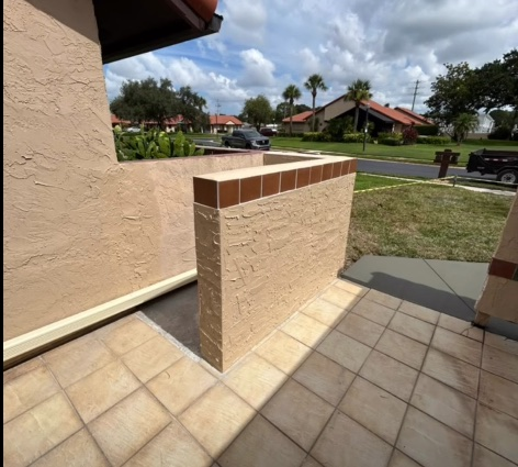 Finished stucco concrete wall with cap detail beside a residential patio.