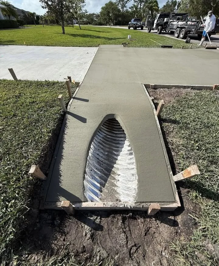 Fresh concrete driveway apron formed around a residential culvert pipe