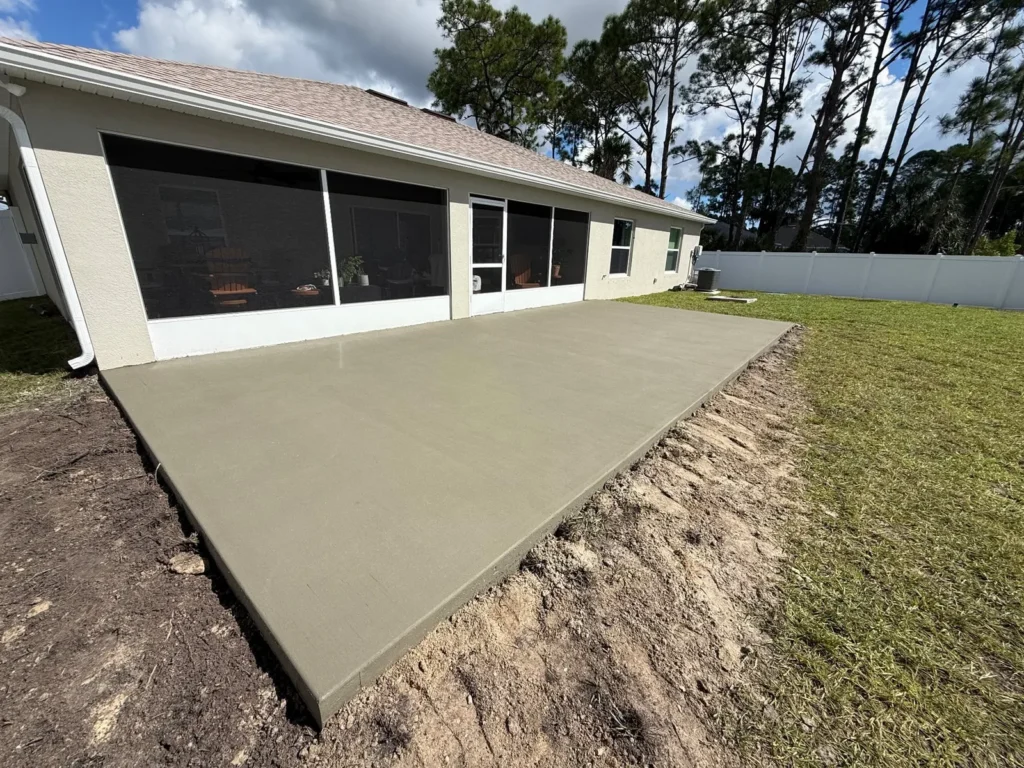 New concrete backyard patio outside a screened room by JCD Concrete