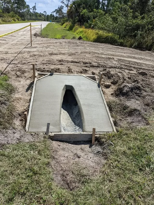 Fresh concrete mitered end treatment around a roadside culvert pipe