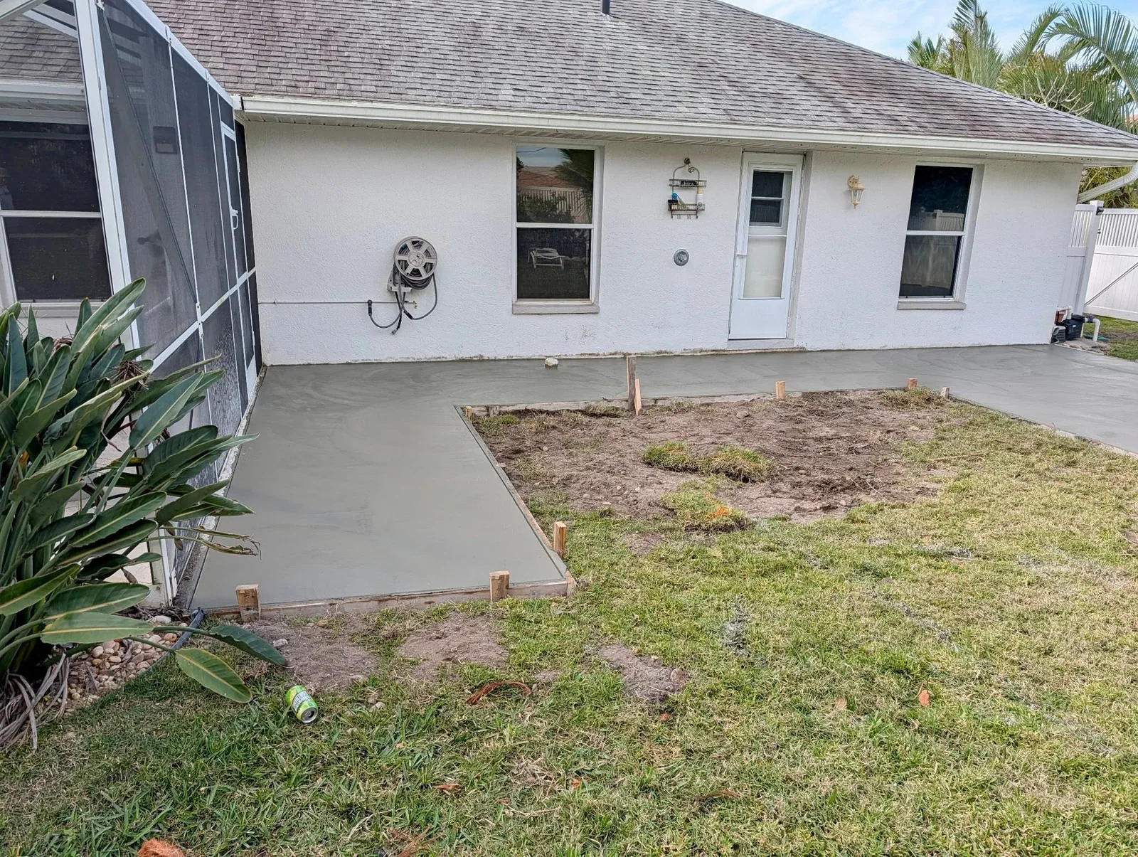 Finished concrete patio and walkway beside a screened enclosure