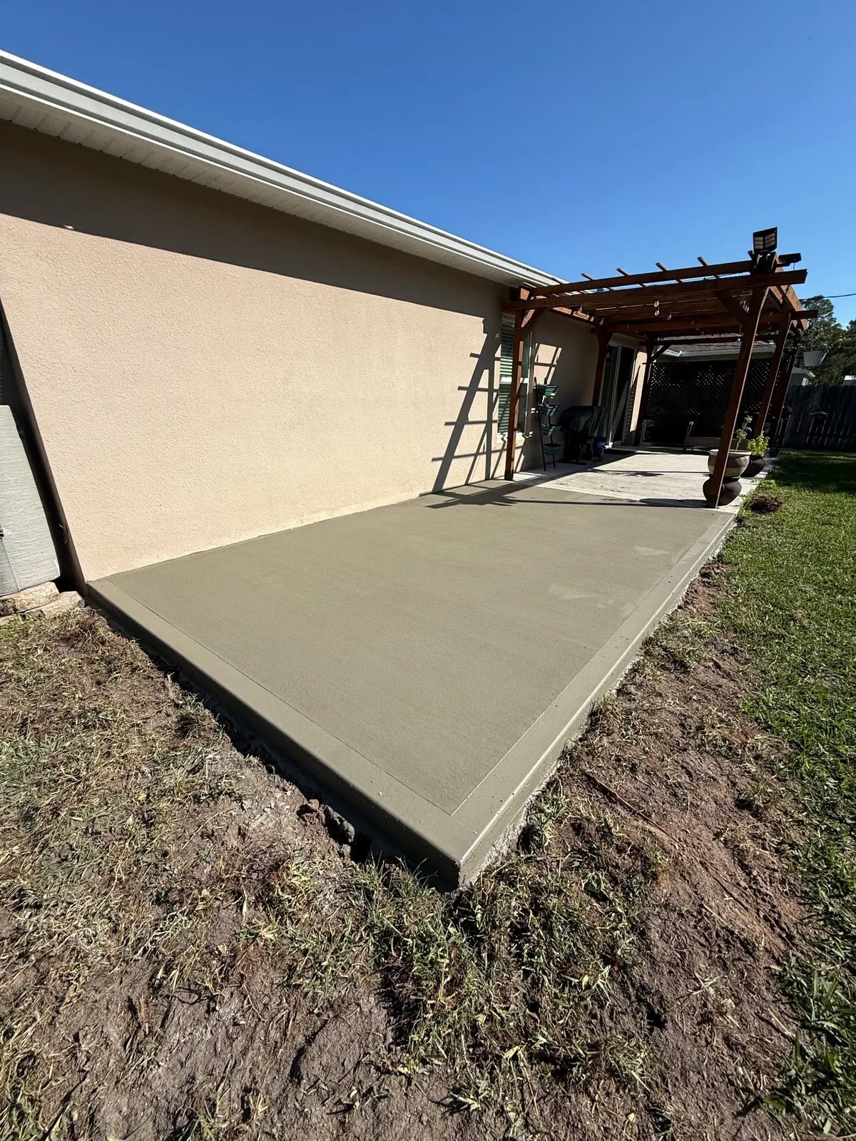 New concrete patio extension beside an existing backyard pergola
