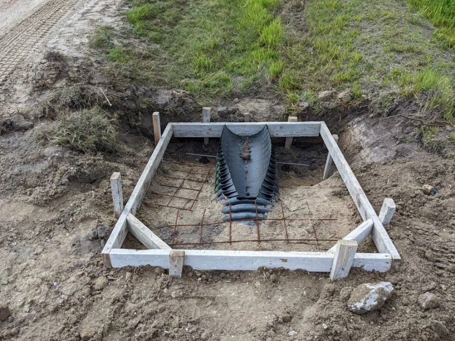 Formwork and steel reinforcement around a driveway culvert pipe before concrete placement