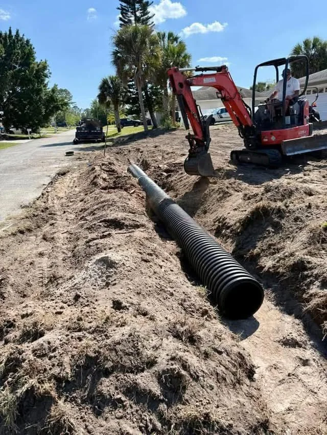 Residential driveway culvert pipe positioned in an excavated drainage trench