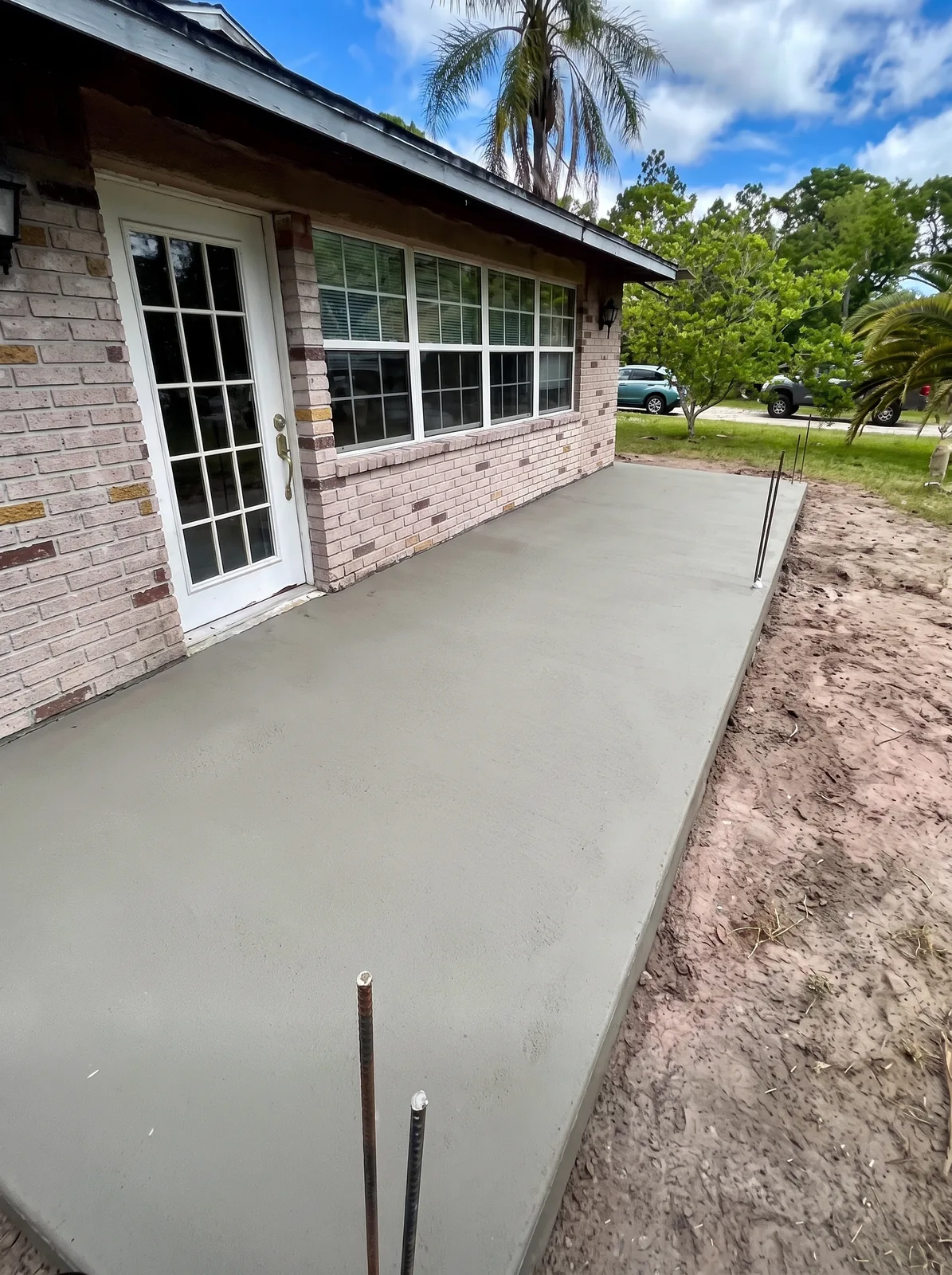 Concrete slab for a house addition with projecting reinforcement beside a brick home