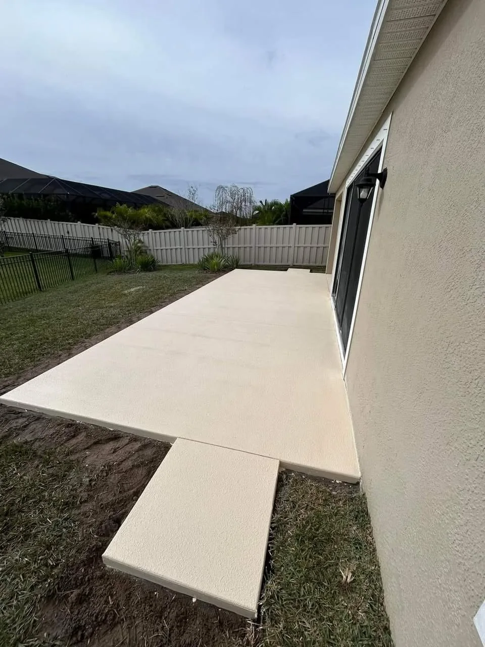 Wide view of a completed residential back patio with a spray-deck finish by JCD Concrete